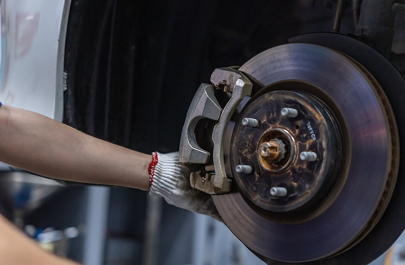 Người thợ đang kiểm tra má phanh xe ô tô để đảm bảo an toàn khi bảo dưỡng ô tô định kỳ