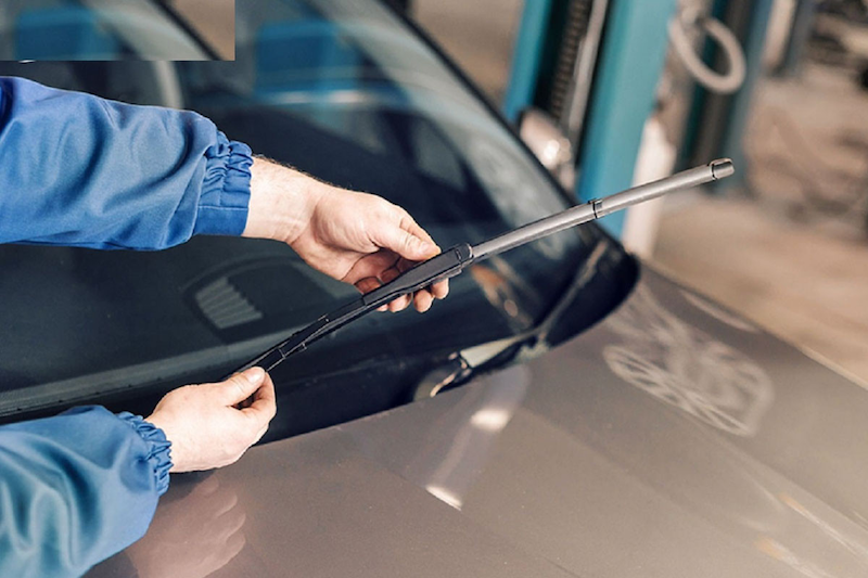 Người thợ đang kiểm tra cần gạt nước xe ô tô để đảm bảo tầm nhìn khi bảo dưỡng ô tô định kỳ